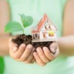 Hands holding a miniature house and plant, illustrating home and growth for Zing Plumbing's leak detection services.