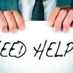 Hands holding a "NEED HELP" sign in formal attire, representing urgent plumbing needs by Zing Plumbing.