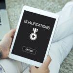 A person holding a tablet displaying "QUALIFICATIONS" and a medal symbol, representing licensed plumbing professionals.