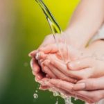 Human hands pouring water with a blurred green background, highlighting Zing Plumbing's focus on water quality and safety.