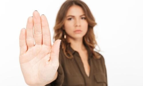Woman holding up hand in a stop gesture, conveying a message of caution or refusal, relevant to plumbing issues and preventative measures.