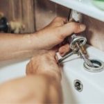 Hands working on plumbing with tools during sink installation, relevant to Zing Plumbing's leak repair services in Tucson.
