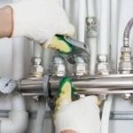 Hands using an adjustable wrench on plumbing pipes and valves, highlighting Zing Plumbing's shower plumbing expertise.