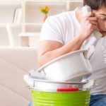 Young man on phone with household items in green bucket, showcasing Zing Plumbing's plumbing emergency prevention tips.