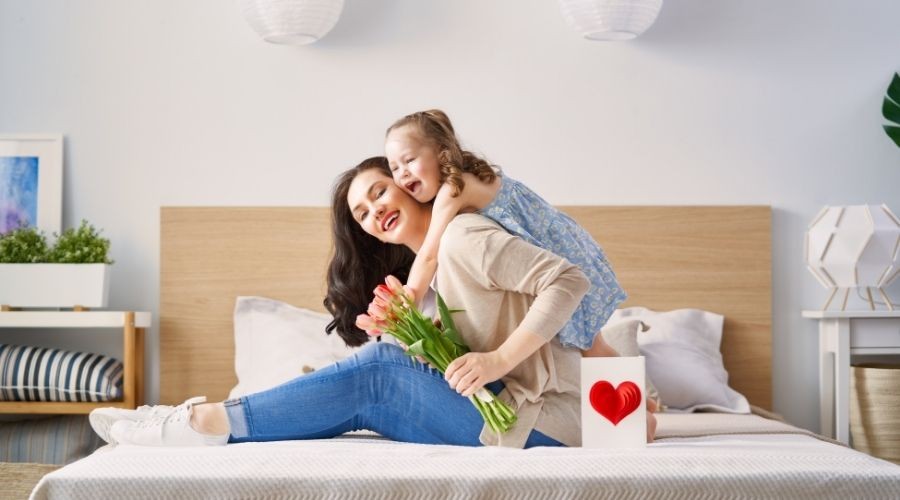 Woman and girl indoors with tulip bouquet and heart gift box, reflecting Zing Plumbing's home services focus.