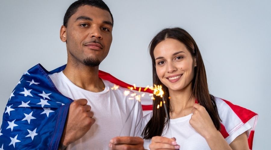 Man and woman with American flags, celebrating Independence Day, representing unity in plumbing service awareness.