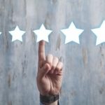 Hand pointing at five stars on textured background, symbolizing evaluation for Zing Plumbing's reliable services in Tucson.