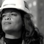 Confident woman in a hard hat represents female empowerment in plumbing, showcasing Adrienne Bennett’s achievements.