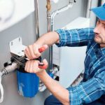 Technician servicing plumbing equipment in a clean workspace, highlighting Zing Plumbing's water filtration expertise.
