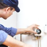 Technician from Zing Plumbing adjusting a wall-mounted thermostat for efficient temperature control in Tucson, AZ.