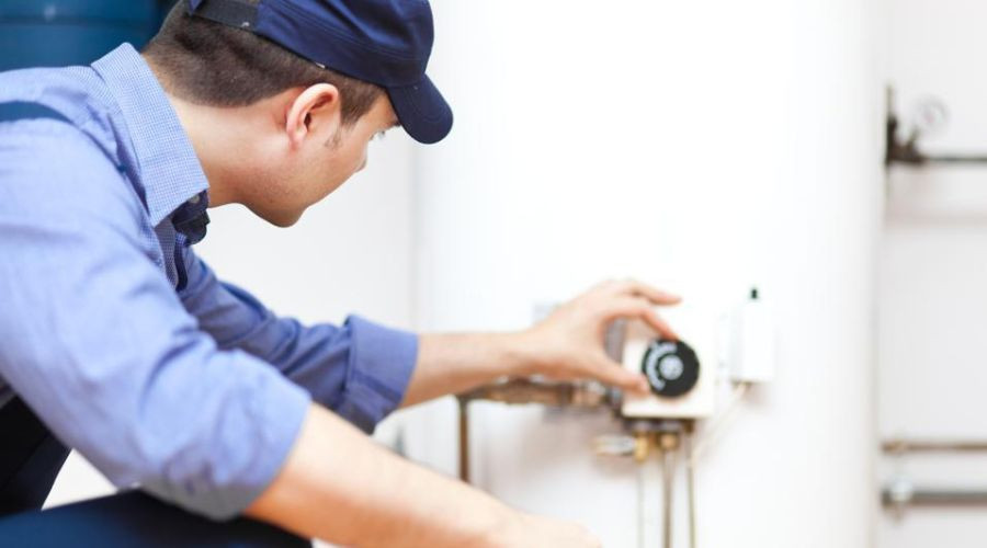 Technician adjusting a water heater for Zing Plumbing, focusing on temperature control and plumbing connections.