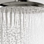 Showerhead with cascading water droplets showcasing a chrome fixture for a relaxing bathroom experience by Zing Plumbing.