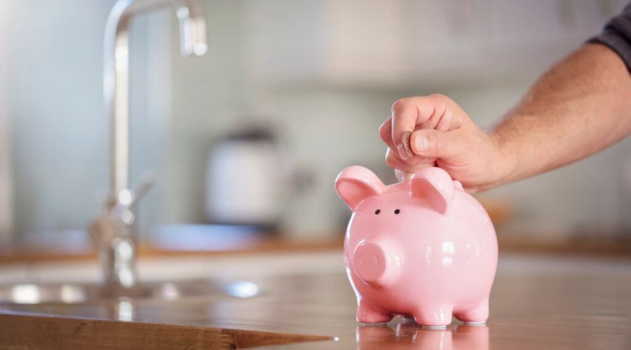 A pink pig-shaped bank with a hand depositing a coin, symbolizing financial responsibility and savings for homeowners.