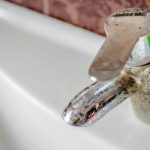 Close-up of a rusty faucet above a white sink, highlighting plumbing issues for Tucson homeowners. Zing Plumbing services.
