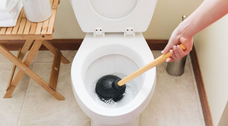 Clean bathroom with a white toilet and plunger, showcasing Zing Plumbing's maintenance focus.