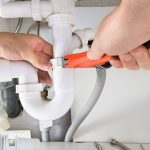 Hands using a wrench on plumbing fixtures, highlighting the importance of regular plumbing maintenance by Zing Plumbing.