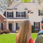 Couple standing in front of a suburban house, highlighting home safety and gas leak awareness.