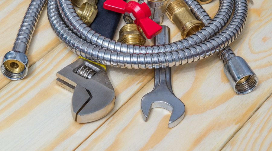 Plumbing tools including a wrench, hose fittings, and a red valve handle for Zing Plumbing maintenance tasks.