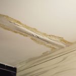 Water-damaged ceiling with exposed drywall and peeling paint, indicating leaks for Zing Plumbing repair services.