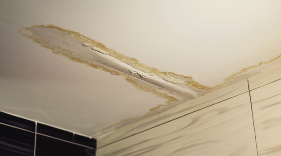 Water damage on a bathroom ceiling with stains and textures, indicating plumbing issues near Zing Plumbing's service area.