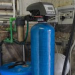 Water softener system featuring a blue tank and control unit, essential for improving hair health by reducing hard water minerals.